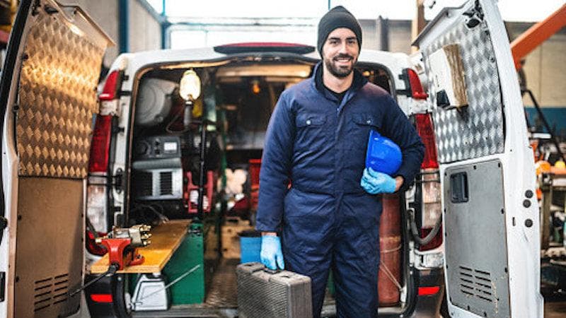 A technician at the open rear of a work van