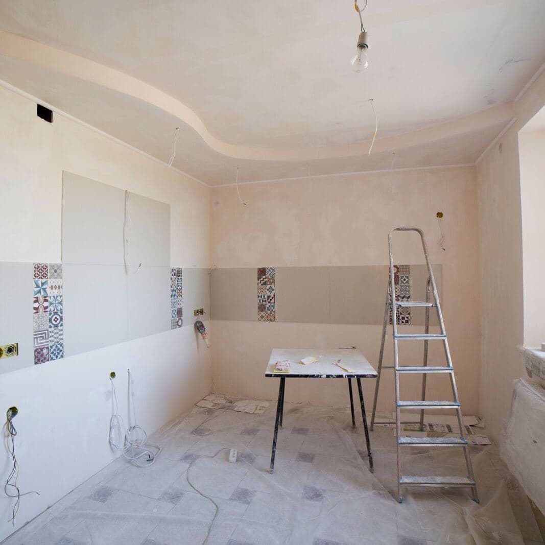 A kitchen stripped back during a renovation, where a renovation policy covers the existing building and the new work