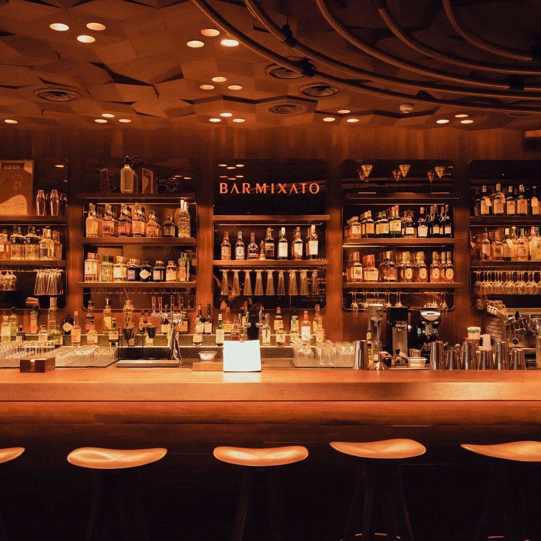 A warmly lit bar with shelves of bottles