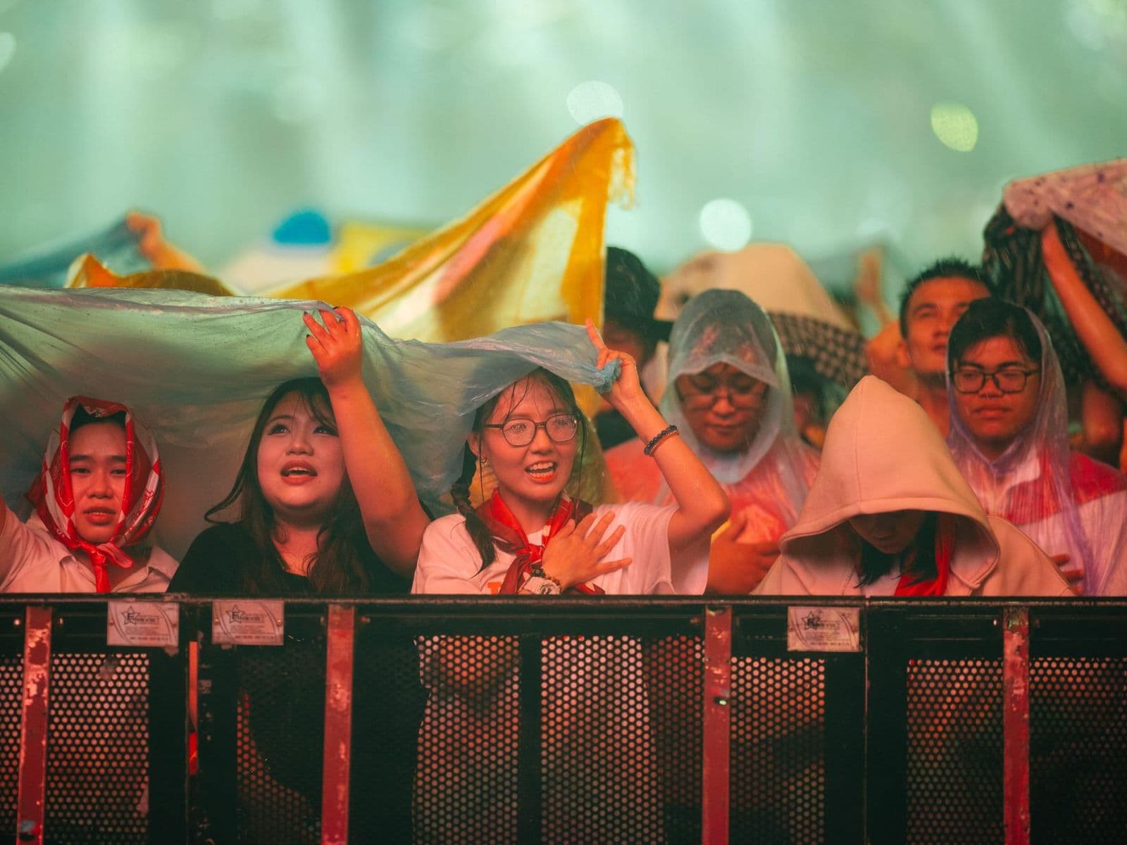 A festival crowd under ponchos in the rain, the weather parametric rain insurance pays out on
