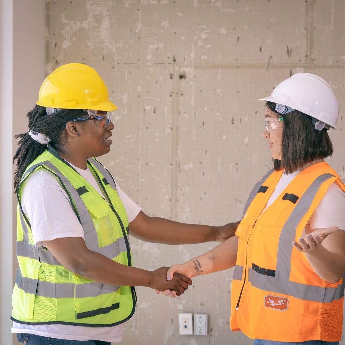 Two contractors in hard hats shaking hands