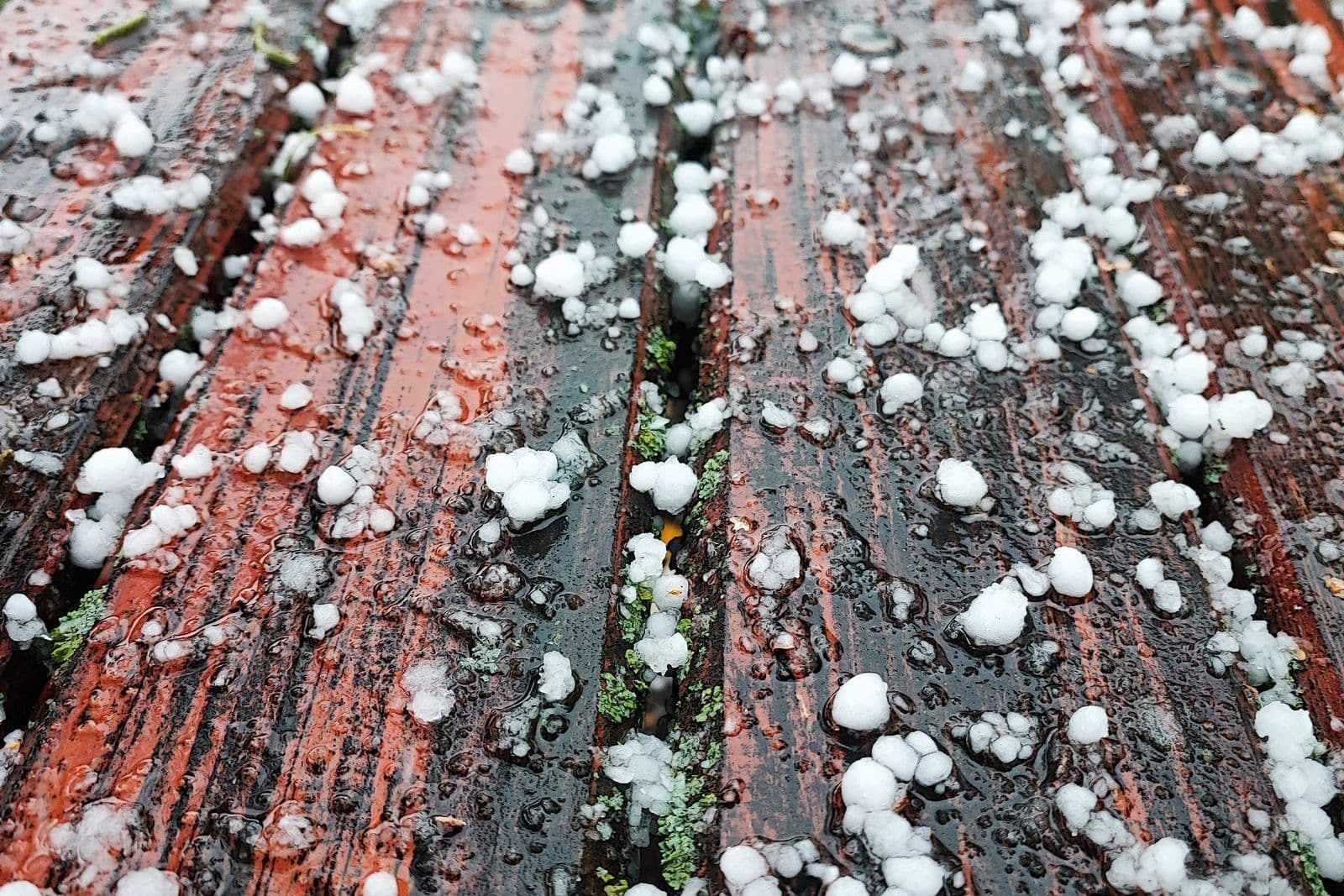 Hailstones on a wooden deck, the storm damage a wind and hail deductible buy-back covers