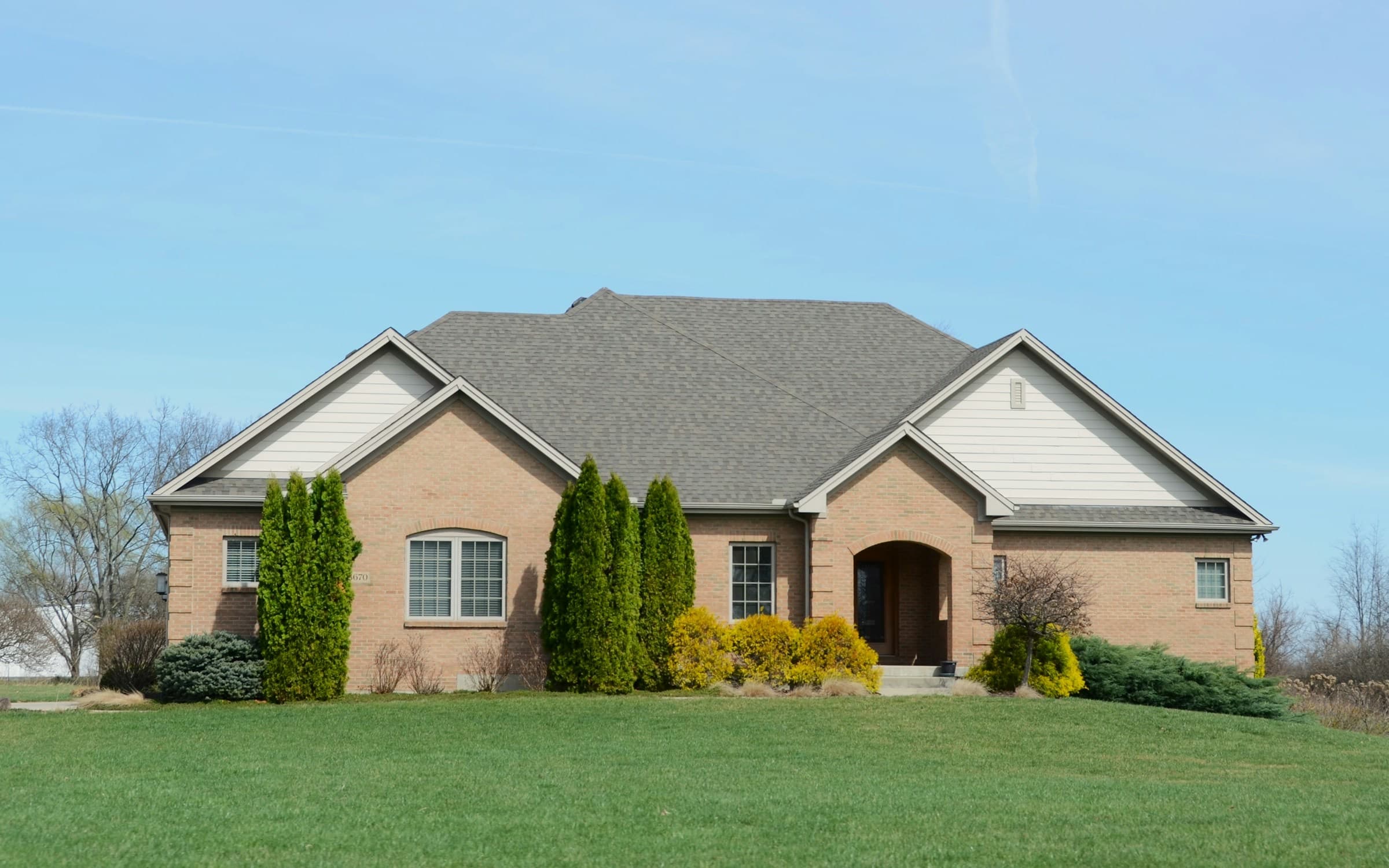 A brick single family house on a wide lawn, the kind of rental or second home a dwelling fire policy insures
