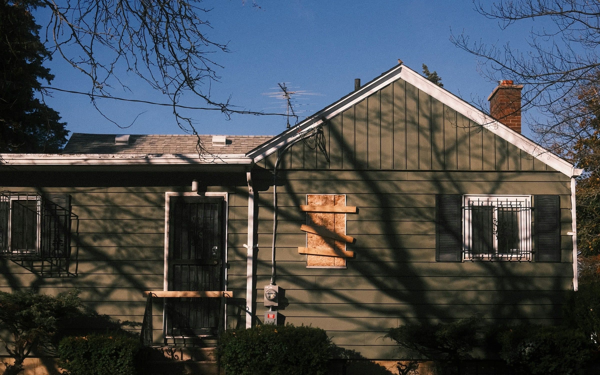 An empty single story house with a boarded up window and barred windows, the kind of vacant home that needs its own vacant property policy