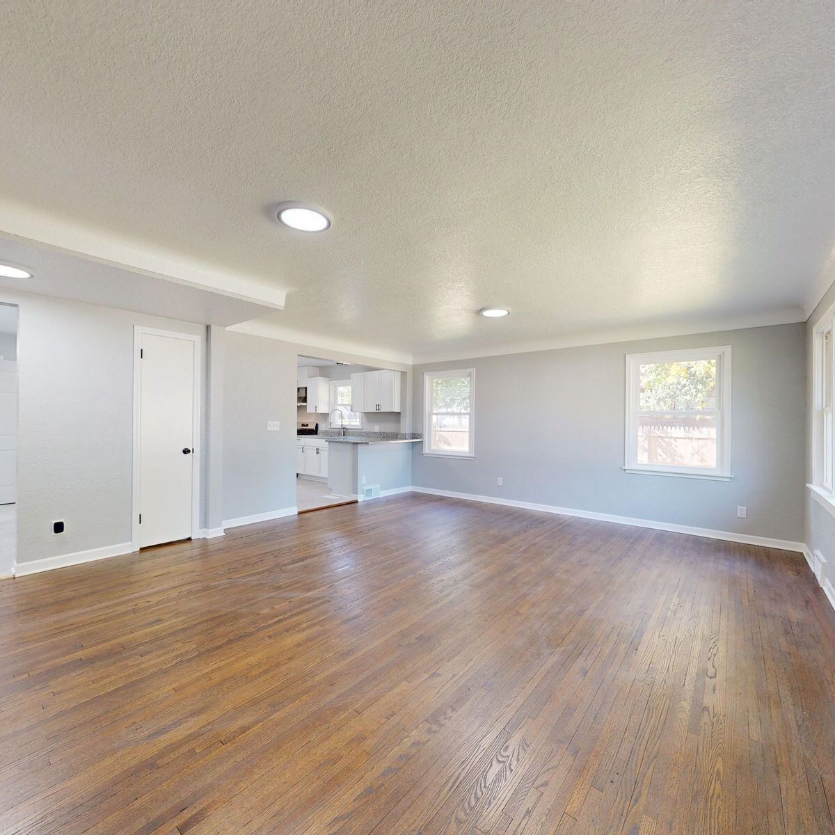 Sala vacía y luminosa con pisos de madera y sin muebles, el tipo de casa desocupada que aseguran estas pólizas